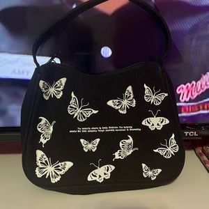 An all black purse with white butterflies and writing